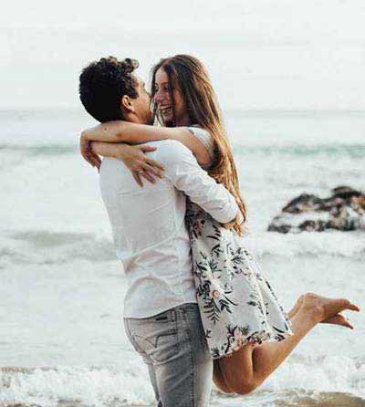 A picture of a man and woman hugging at a seashore