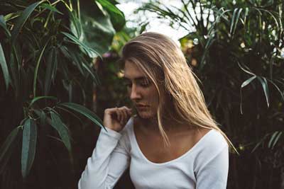 A photo of a beautiful blonde woman with tall plants in the background